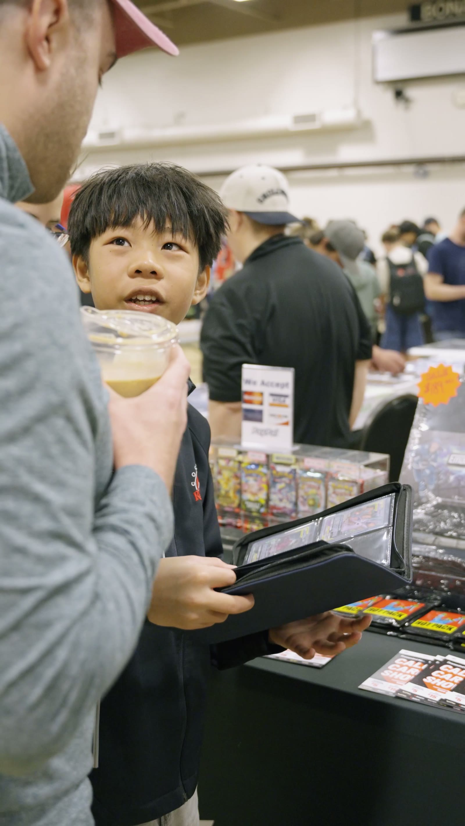 A young collector opening a binder at a vendor table
